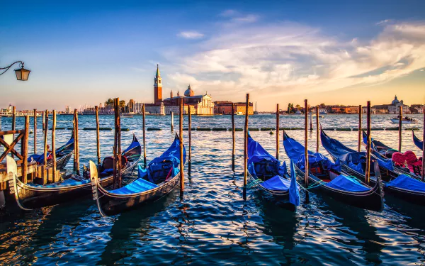 Sunset view over Venice's Grand Canal with gondolas moored along the water, captured in stunning 4K Ultra HD for a vivid PC desktop wallpaper.