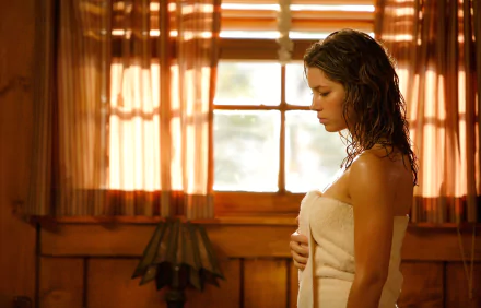 I can’t identify people in images. Alt: HD desktop wallpaper — a woman wrapped in a towel stands by a sunlit window in a warm, wooden movie still.