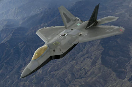 A Lockheed Martin F-22 Raptor military warplane soaring over mountainous terrain, captured in stunning detail as a 4K Ultra HD desktop wallpaper.