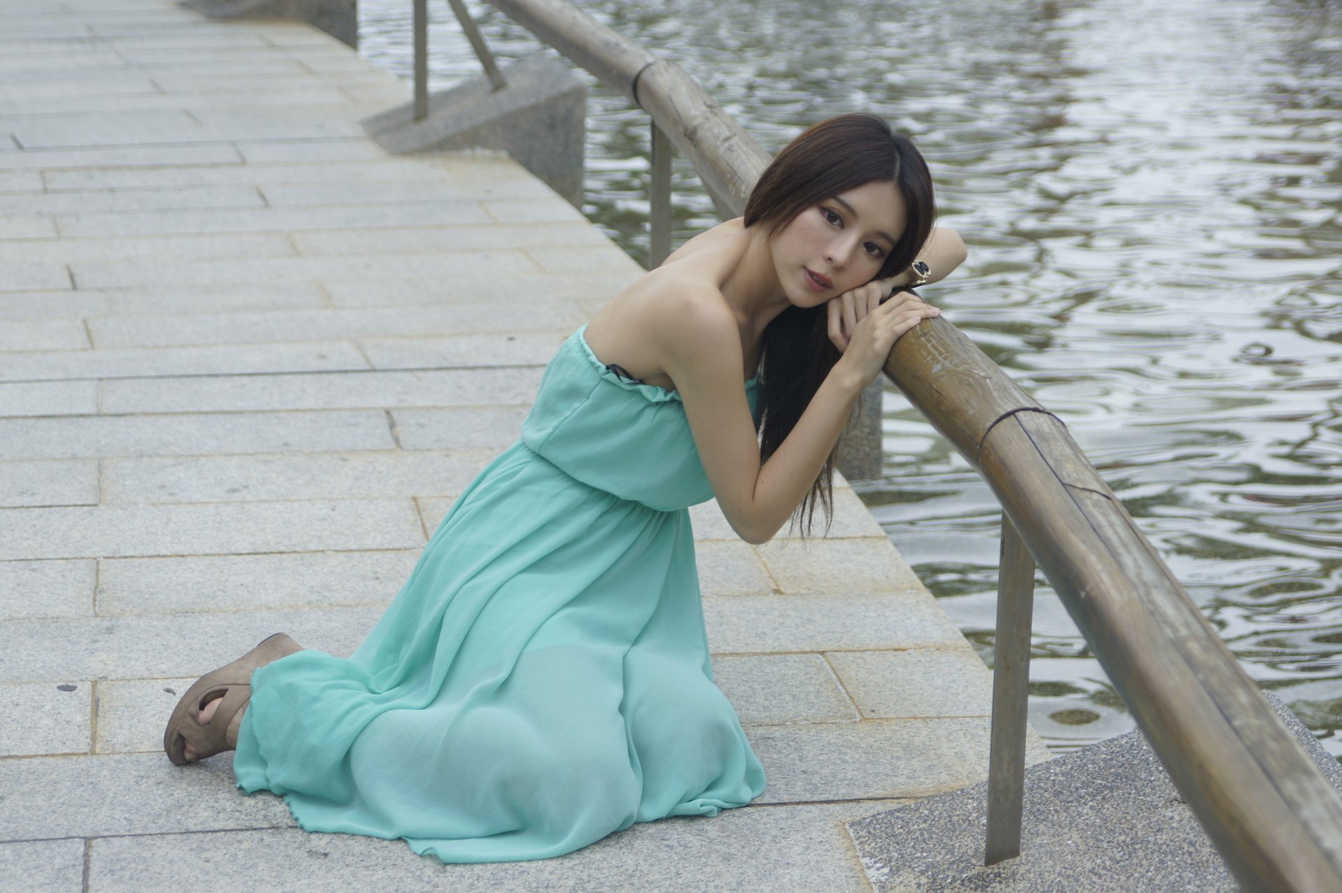 Taiwanese model Julie Chang poses by the water in Hong Kong, wearing a flowing turquoise dress, captured in a 4K Ultra HD desktop wallpaper by Zhang Qi Jun.