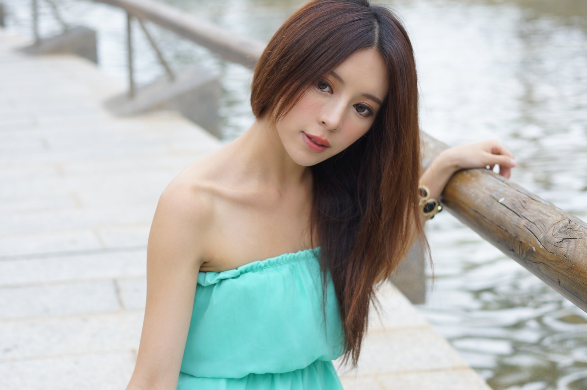 Portrait of Taiwanese model Julie Chang wearing a turquoise dress and bracelet by the water in Hong Kong, captured in 4K Ultra HD for a PC desktop wallpaper.
