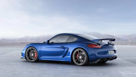 Blue Porsche Cayman GT4 sports car, side-rear view on open concrete — HD PC desktop wallpaper background showcasing the Porsche Cayman vehicle's aerodynamic wing and alloy wheels.