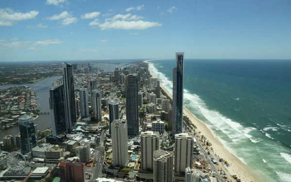 Aerial 5K Ultra HD PC desktop background of Gold Coast, Queensland, Australia: oceanfront cityscape with man-made skyscrapers, sandy beach and the Pacific Ocean stretching to the horizon.