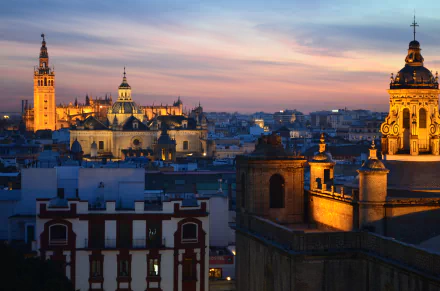 A stunning twilight view of Seville, Spain, showcasing its majestic cathedrals illuminated against the night sky, highlighting the city's rich architectural beauty.