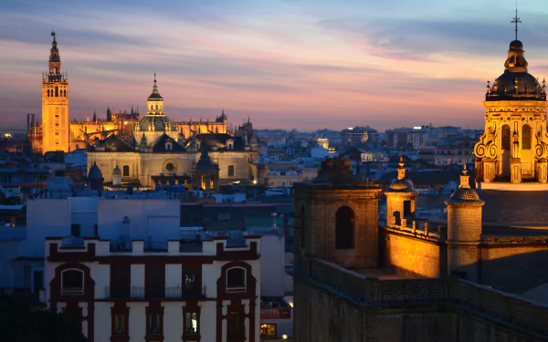 A stunning twilight view of Seville, Spain, showcasing its majestic cathedrals illuminated against the night sky, highlighting the city's rich architectural beauty.