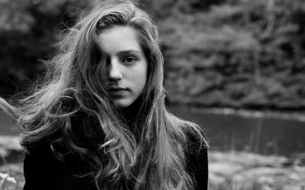 Black and white HD desktop background featuring Birdy, the English singer, with flowing hair and a serene expression against a natural backdrop.