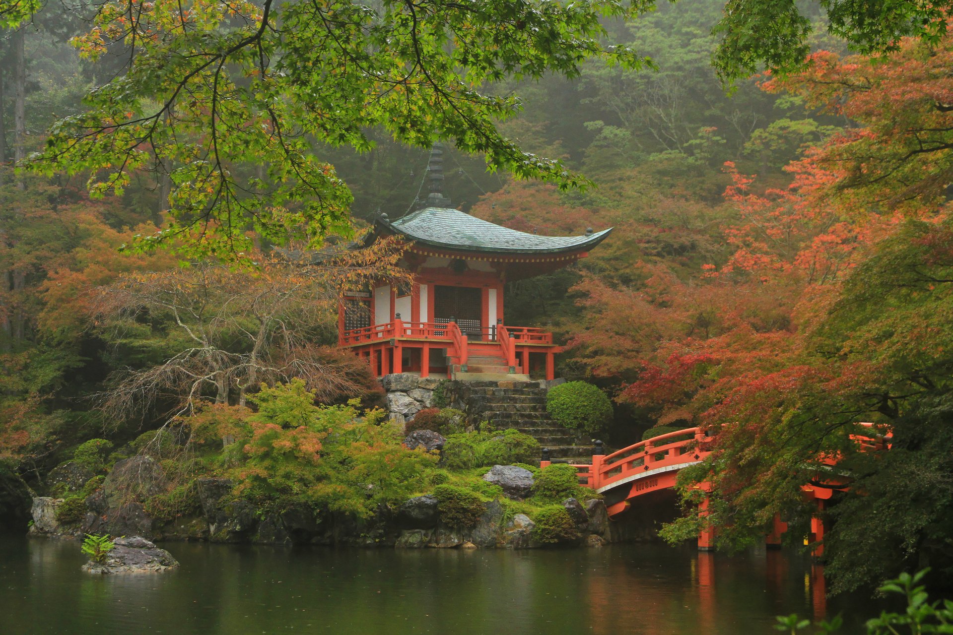 Daigo-ji temple shrine and pagoda in Kyoto surrounded by vibrant fall foliage, reflected in a serene pond. 4K Ultra HD desktop wallpaper showcasing religious beauty.