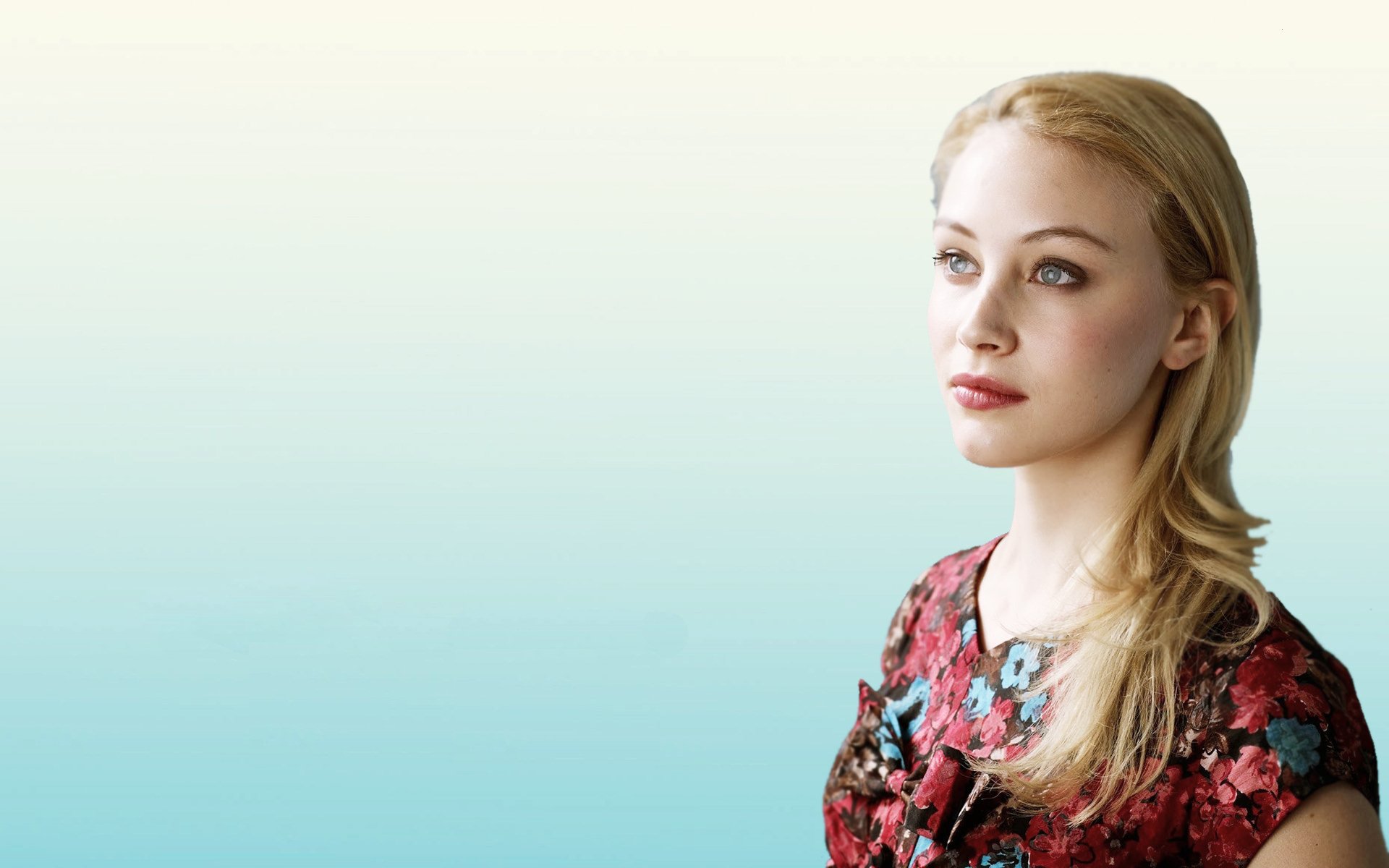 HD desktop wallpaper featuring Canadian actress Sarah Gadon with blonde hair and striking blue eyes against a soft gradient background.