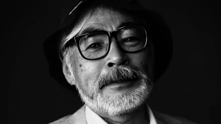 Black and white HD wallpaper of a bespectacled man with a hat, reminiscent of Hayao Miyazaki, providing an elegant background.