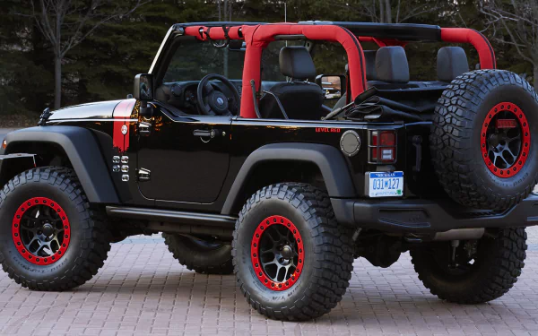 A stylish Jeep Wrangler Level Red, featuring a bold black exterior with red accents, stands ready for adventure. This rugged 4x4 vehicle embodies off-road capability.