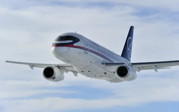 Sukhoi SuperJet 100 jet airplane flying against a cloudy sky, captured in 4K Ultra HD as a PC desktop wallpaper and background.