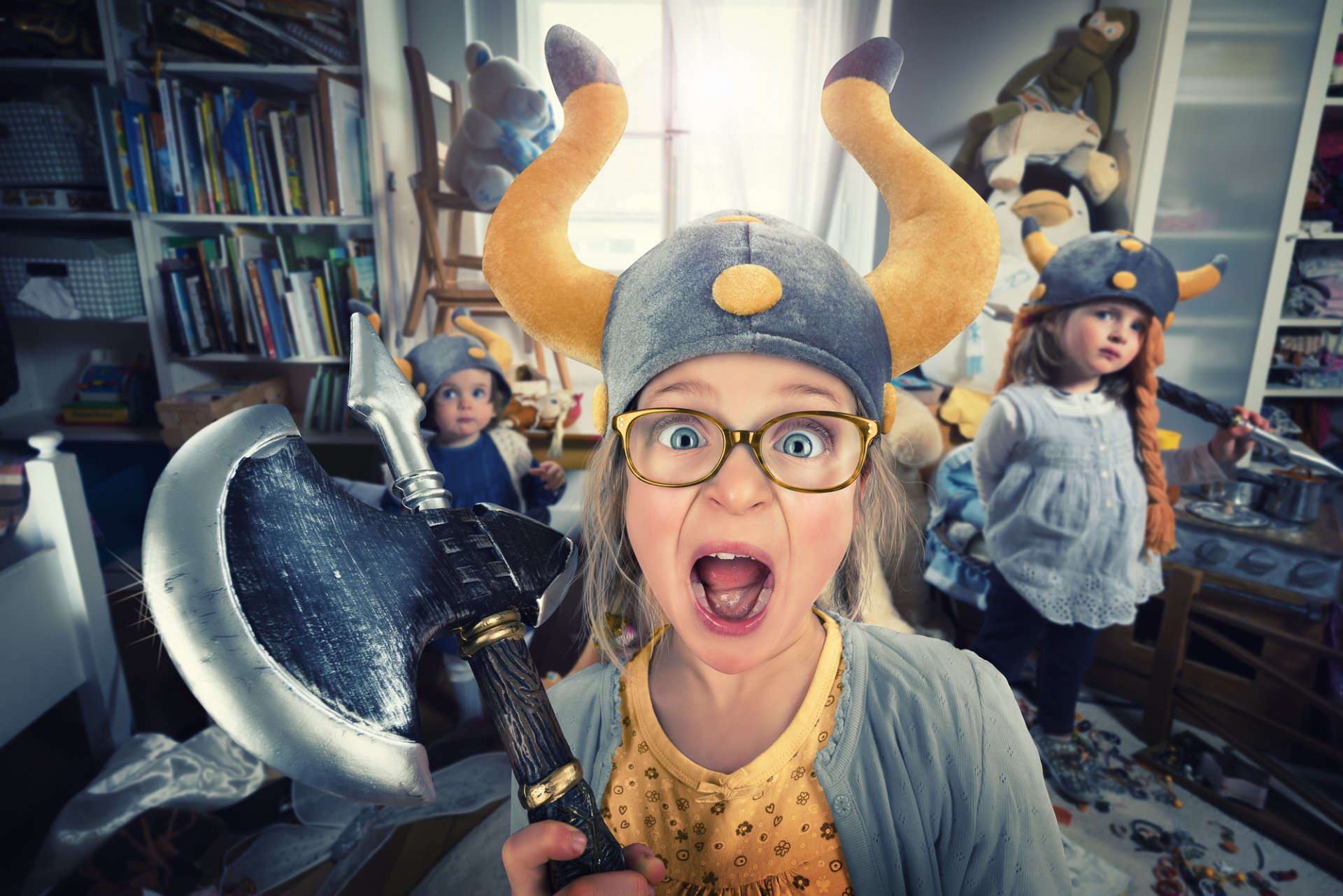 A humorous HD desktop wallpaper featuring a child dressed as a Viking, wearing a horned helmet and holding an axe, with playful expressions in a cluttered room.
