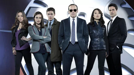 HD PC desktop wallpaper featuring the main cast of the TV show Agents of S.H.I.E.L.D. standing in front of the iconic S.H.I.E.L.D. logo.