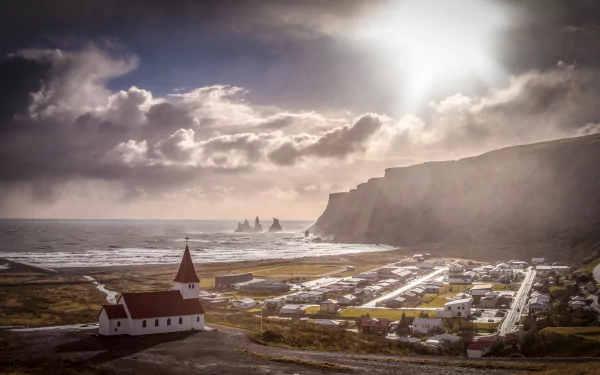 A stunning sunset over the coastline of Vík í Mýrdal, Iceland, featuring a quaint church and dramatic cliffs by the sea, captured in vibrant 4K Ultra HD.