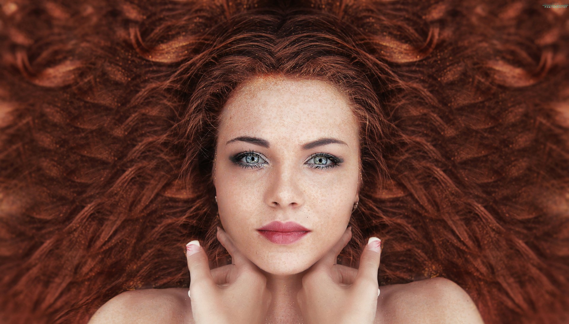 Stunning HD wallpaper featuring a redhead woman with blue eyes. Her beautiful face and hair, styled in flowing waves, make an eye-catching background.
