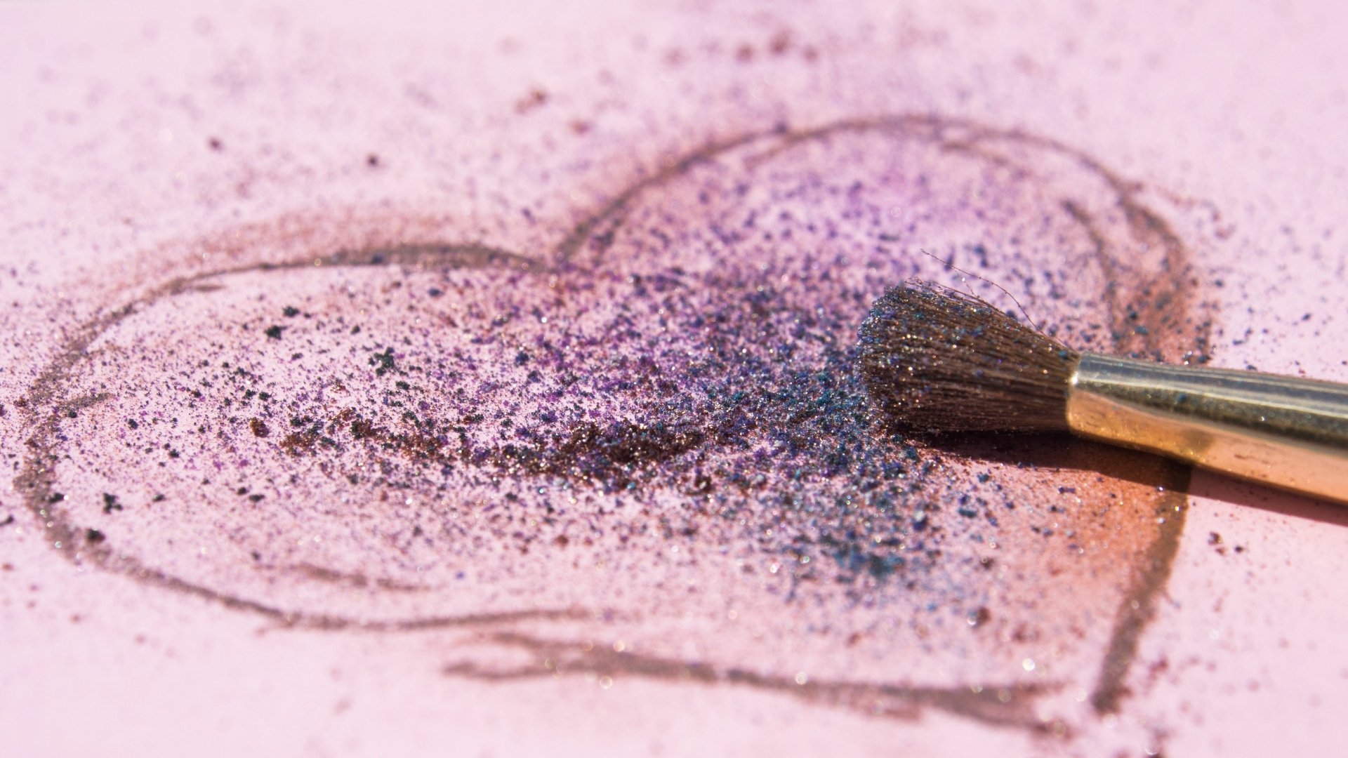 A HD desktop wallpaper featuring a heart drawn with purple and black powder, with a brush resting on it, conveying a sense of artistic love.