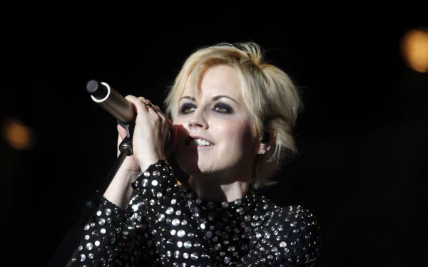 Blonde female singer in a sequined jacket singing into a microphone on stage — HD PC desktop wallpaper and music background.