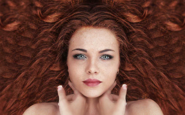 Stunning HD wallpaper featuring a redhead woman with blue eyes. Her beautiful face and hair, styled in flowing waves, make an eye-catching background.