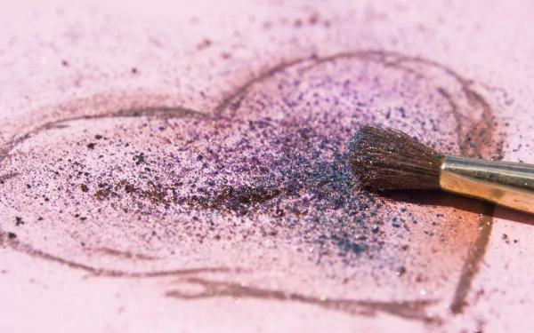 A HD desktop wallpaper featuring a heart drawn with purple and black powder, with a brush resting on it, conveying a sense of artistic love.