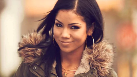 HD PC desktop wallpaper of a smiling R&B music artist in a fur-trimmed coat and hoop earrings, warm blurred background