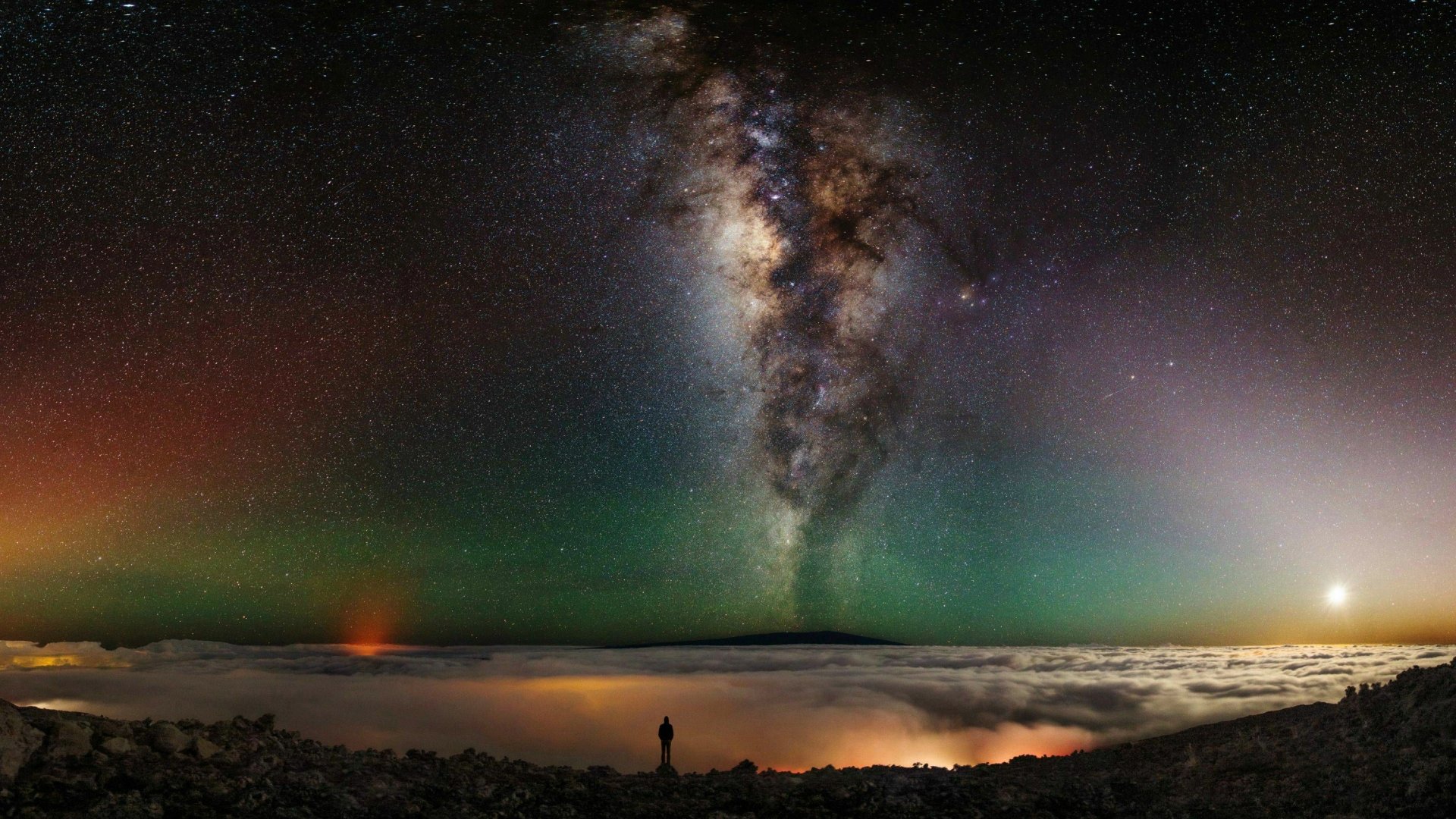 A breathtaking Sci-Fi landscape featuring the Milky Way galaxy, with vibrant colors and a lone figure gazing at the starry sky, serves as a stunning HD desktop wallpaper.