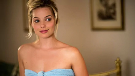 HD movie-themed PC desktop wallpaper: soft-focus portrait of a blonde woman smiling, wrapped in a blue towel against a blurred bedroom background.