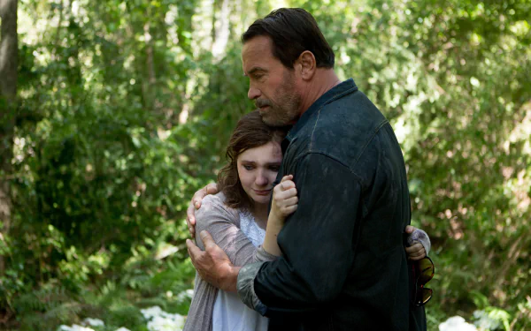 Still from the movie Maggie (2015) showing a man and young woman embracing in a lush forest, presented as a 4K Ultra HD PC desktop wallpaper and background.