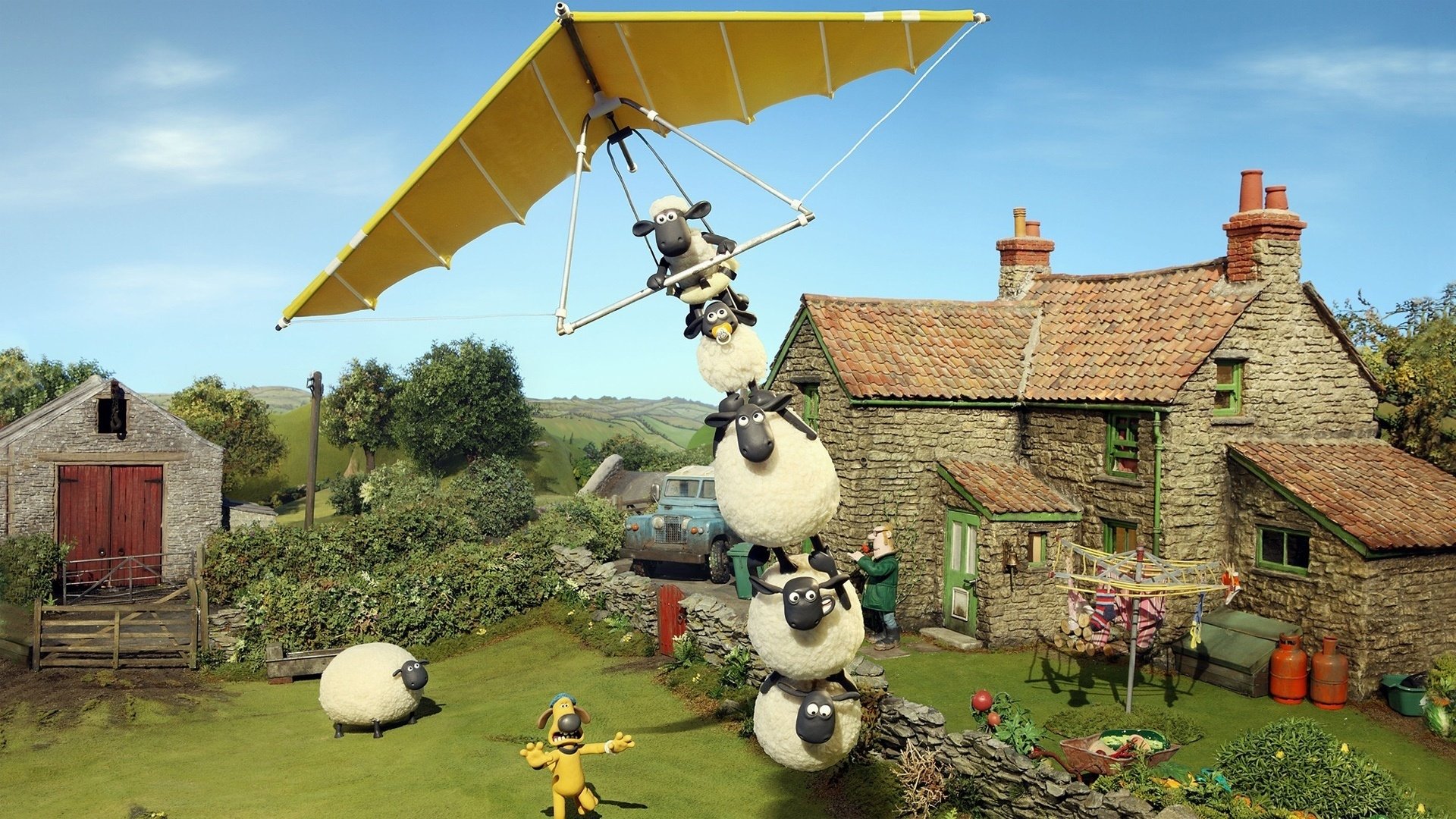Shaun the Sheep Movie HD PC desktop wallpaper and background: Shaun and the flock stack into a tower to launch a yellow hang-glider above a rustic cottage and green countryside.