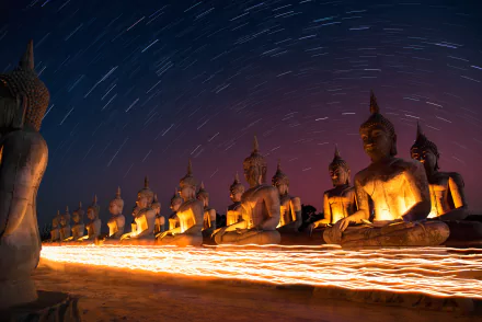A serene nighttime time-lapse of illuminated Buddha statues against a starry sky, creating a peaceful and contemplative atmosphere in this HD wallpaper.