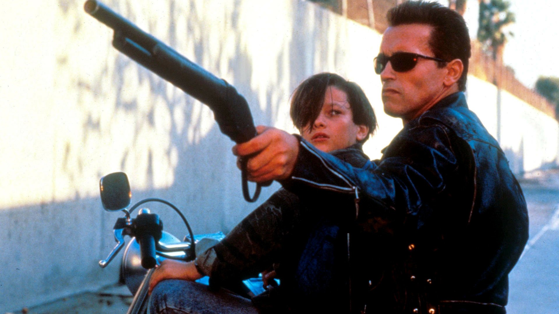 A dynamic scene from Terminator 2: Judgment Day featuring Arnold Schwarzenegger as the Terminator and Edward Furlong as John Connor, showcasing intense action and adventure.
