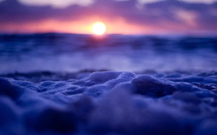 2K Quad HD PC wallpaper: close-up ocean foam in foreground with purple-orange sunset over the horizon, serene nature scene.