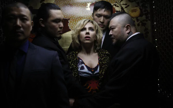 Scarlett Johansson in a tense scene from the movie Lucy, surrounded by men, featured in a 4K Ultra HD PC desktop wallpaper and background.