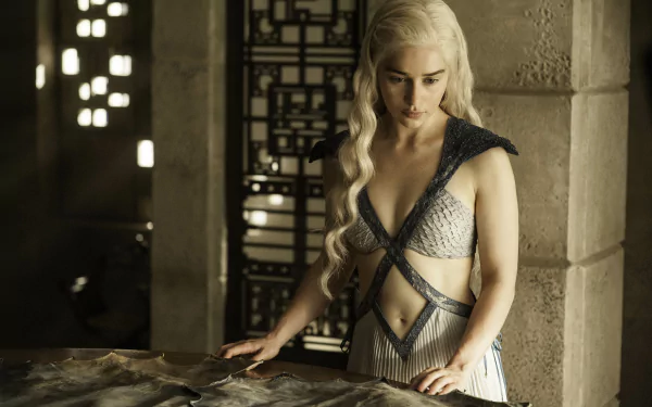 HD desktop wallpaper featuring Emilia Clarke as Daenerys Targaryen in Game of Thrones, standing by a table and looking down intently. The background includes intricate decor from the show's set.