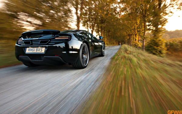 HD desktop wallpaper showcasing a sleek black McLaren MP4-12C speeding down a tree-lined road in autumn.