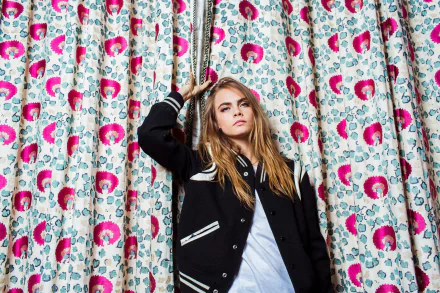 HD PC desktop wallpaper featuring celebrity Cara Delevingne posing confidently in front of a vibrant, floral-patterned curtain.