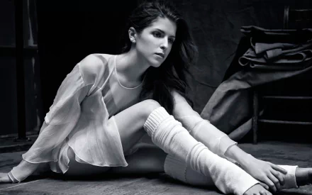 HD PC desktop wallpaper of a celebrity (identity unknown) in a black-and-white studio portrait, seated on the floor wearing a sheer top and leg warmers.