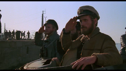 HD PC desktop wallpaper background from the movie Das Boot: two sailors saluting atop a U-boat conning tower, crew silhouettes and quay in the hazy morning light.
