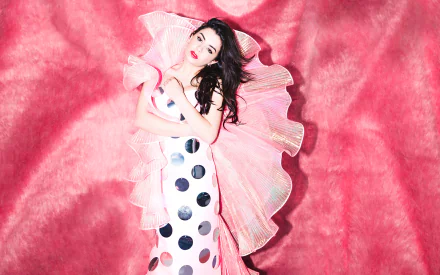 HD PC desktop wallpaper of Charli XCX in a white dress with black polka dots, posing against a vibrant pink textured background.
