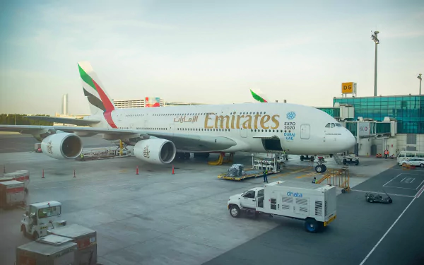 An Airbus A380 aircraft painted in Emirates livery is parked at the terminal, with ground vehicles and infrastructure visible, captured in a vibrant 4K Ultra HD backdrop.