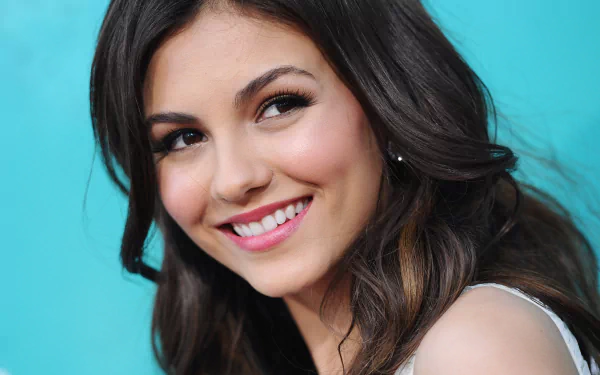 HD desktop wallpaper featuring a close-up of celebrity Victoria Justice smiling against a turquoise background.