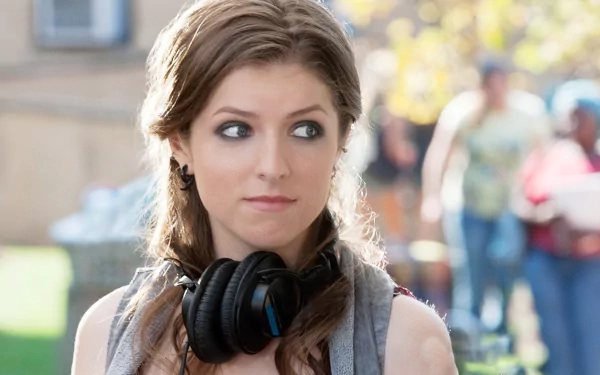 HD desktop wallpaper featuring Anna Kendrick from the movie Pitch Perfect 2, showing her outdoors with headphones around her neck.