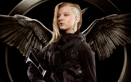 Cressida, portrayed by Natalie Dormer, stands confidently with wings behind her, showcasing her fierce character from The Hunger Games: Mockingjay - Part 1. HD desktop wallpaper.