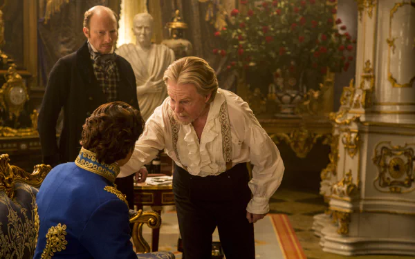 Man in ruffled white shirt leans toward a seated officer in blue coat while another watches in an ornate palace interior — Cinderella (2015) 5K Ultra HD PC desktop wallpaper.