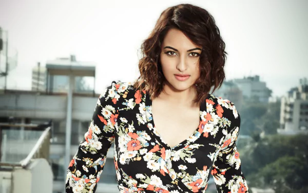 HD desktop wallpaper featuring celebrity Sonakshi Sinha, posing outdoors against an urban background, wearing a floral dress.