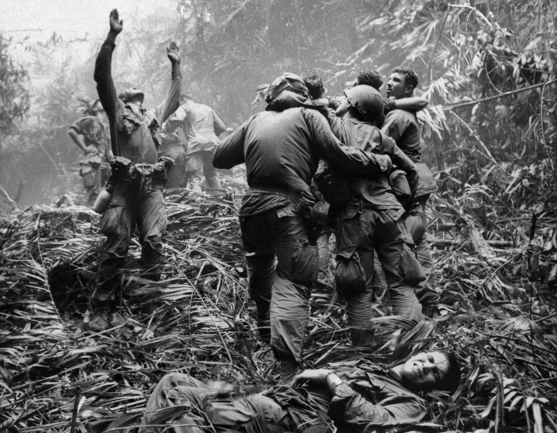 Black-and-white Vietnam War military scene: soldiers carrying a comrade through dense jungle, another person lying in the foreground — HD PC desktop wallpaper and background.
