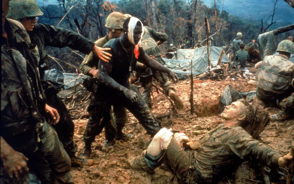 Vietnam War military scene showing soldiers aiding a wounded comrade in a muddy, forested battlefield, captured in high-definition for a PC desktop wallpaper.