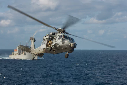 Military Sikorsky SH-60 Seahawk helicopter in flight over the ocean, captured in high-definition as a dynamic PC desktop wallpaper background.