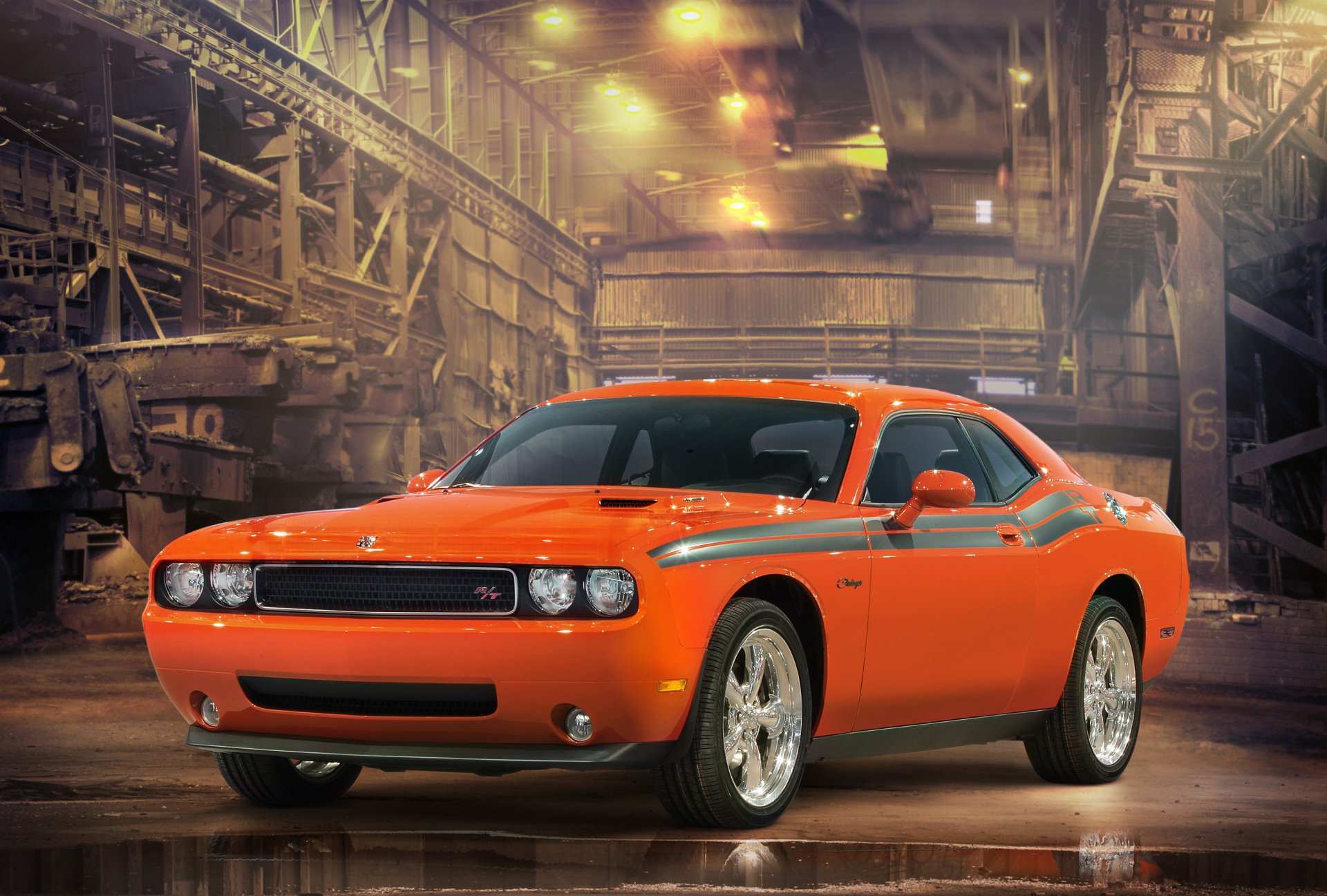 HD desktop wallpaper featuring a bright orange Dodge Challenger parked inside an industrial warehouse with warm lighting and detailed textures.