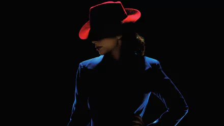 Hayley Atwell as Peggy Carter, exuding vintage charm in a striking blue suit and red hat, set against a dark backdrop. This HD wallpaper captures the essence of *Agent Carter*.