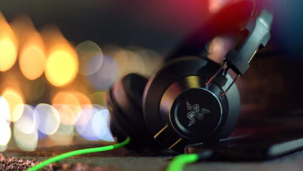A high-definition desktop wallpaper featuring Razer headphones, showcasing sleek design and vibrant green accents against a blurred, colorful background.